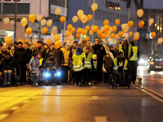 Uczestnicy piątkowego marszu niosą pomarańczowe balony z imieniem Michała.