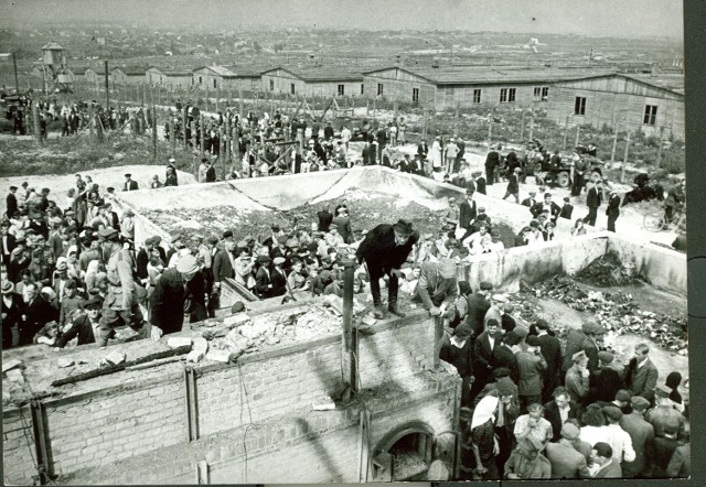 Lipiec 1944 roku. Mieszkańcy Lublina oglądają Majdanek. Na pierwszym planie zniszczone przez Niemców, dla zatarcia śladów ich zbrodni, krematorium. W głębie baraki na V polu (obecnie nie istnieją).