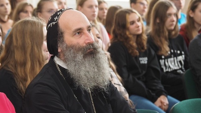 - Nie doceniamy tego, co mamy, dopóki tego nie stracimy. Kiedy straciliśmy szkoły i kościoły, zrozumieliśmy, jak są ważne. Proszę, doceniajcie to, co macie - powiedział ksiądz Petros Butrus Kassis. Z licealistami podzielił się świadectwem posługi w kraju dotkniętym dramatem wojny. Na dziesięć dni do Polski przyjechały delegacje z Kościoła syriacko-prawosławnego i organizacji Christian Hope Center Aleppo. Syryjczycy odwiedzili Warszawę i Białystok. Będą m.in. w Katowicach i Lublinie. W Koszalinie z uczniami V Liceum Ogólnokształcącego spotkał się ksiądz Petros Butrus Kassis, wikariusz patriarchalny kościoła syriacko-prawosławnego w Aleppo. Wybór szkoły nie był przypadkowy - spotkanie wpisało się w obchody Dnia Wolontariusza, a wolontariat wśród uczniów działa bardzo prężnie. W ubiegłym roku 9 uczniów Szkolnego Koła Caritas pracowało w sierocińcu polskich elżbietanek w Betlejem. Licealiści pomagali także w ośrodku prowadzonym przez argentyńskie zakonnice dla głęboko upośledzonych dzieci.Tym razem mogli usłyszeć m.in. o programie „Rodzina Rodzinie” Caritas Polska, który realizowany jest w Syrii. - Nasi goście przyjechali z Aleppo. Przez wieki miasto znane było z produkcji oliwy z oliwek, mydła i pistacji. Było tu wiele fabryk, warsztatów. Dziś to obraz zniszczeń wojennych - powiedziała Sylwia Hazbun z Caritas Polska.Ksiądz Petros Butrus Kassis opowiadał uczniom o  udręczonej wojną Syrii. Pokazywał zdjęcia dzieci, które dźwigają do ruin domów wodę. - Zamiast chodzić do szkoły, pracują po kilkanaście godzin dziennie za cztery dolary tygodniowo - opisywał. - Dzieci widziały wszystkie zbrodnie. Wojna jest w nich głęboko zakorzeniona. Tak głęboko, że dziś ich ulubioną zabawką jest broń.Duchowny mówił o oblężonych miastach. O ojcu, który jednego dnia pochował sześcioro dzieci. O zastrzelonym na półkolonii chłopcu. - Mówię to, byście doceniali pokój i zawsze starali się go zachować. Jakakolwiek różnica zdań, czy to polityczna czy obyczajowa, nie może prowadzić  do konfliktu - zaakcentował o. Kassis. Podziękował też  za pomoc, którą Syryjczycy dostają od Polaków. - Dzięki waszemu wsparciu nasze życie zmienia się na lepsze. Współpraca z Polakami jest odpowiedzią na nasze modlitwy - powiedział.Przykłady można mnożyć. Pieniądze z programu „Rodzina rodzinie” Caritas to często jedyne środki na życie dla wielu seniorów i dzieci. A jeśli ktoś w zeszłym roku w wigilię postawił na stole świecę Caritasu, może powiedzieć - pomogłem odbudować szkołę, która otworzyła drzwi dla 800 dzieci. - Niestety, wojna się jeszcze nie skończyła - dodał Petros Butrus Kassis, pokazując zdjęcia z maja tego roku, kiedy pociski spadły na dom jednego z jego parafian. - Spokój i pokój nie wrócił jeszcze do naszego miasta. Mam nadzieję, że kiedyś będziecie mogli odwiedzić mój kraj i zobaczycie go tak pięknym, jak ja widzę dziś Polskę. Zobacz także: Koszalin: 70-lecie koszalińskiego "Bronka"