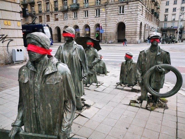 Czerwone opaski na figurach Pomnika Anonimowego Przechodnia we Wrocławiu
