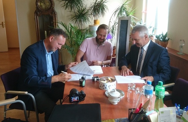 Skarbnik gminy ( z lewej) oraz burmistrz (z prawej ) podpisują umowę na dofinansowanie kolejnego odcinka drogi w gminie.