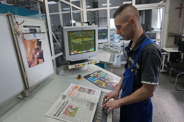 Adam Anisimowicz z dyżurki kontroluje pracę maszyny drukarskiej. Ustawia w komputerze kolory, dba o właściwe parametry. Wszystko po to, by grafika ładnie wyglądała. Na tym stanowisku pracuje od dwóch lat, natomiast w drukarni - w sumie 12. W wolnych chwilach też chętnie czyta „GW“