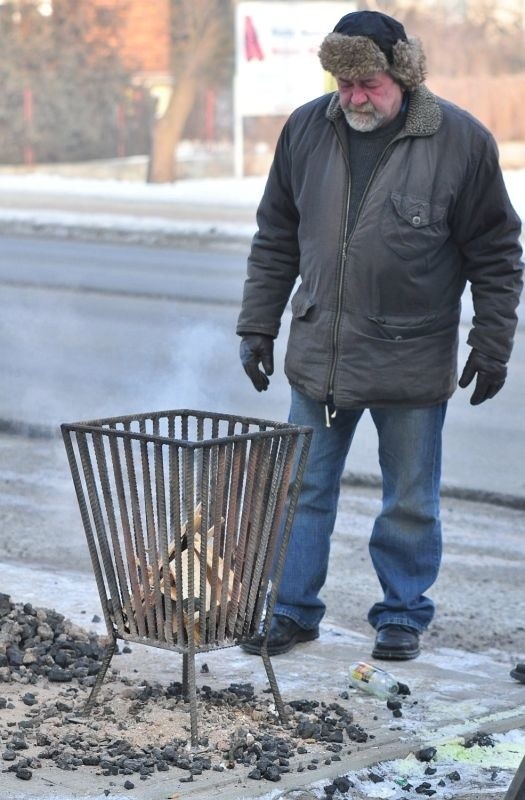 Pracownik gospodarczy z tarnobrzeskiego Urzędu Miasta rozpala ogień w koksowniku przy wiacie autobusowej na ulicy Sienkiewicza.