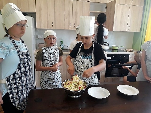 W stroju szefa kuchni mali kucharze przyrządzają wspólne posiłki. To jeden z wielu kroków w dorosłe życie