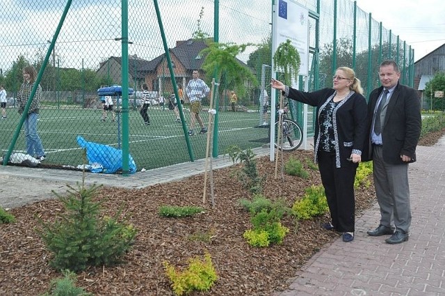 Wójt Barbara Matysiak i jej zastępca Michał Pękala pokazują nowe rośliny nasadzone przy szkolnym boisku.