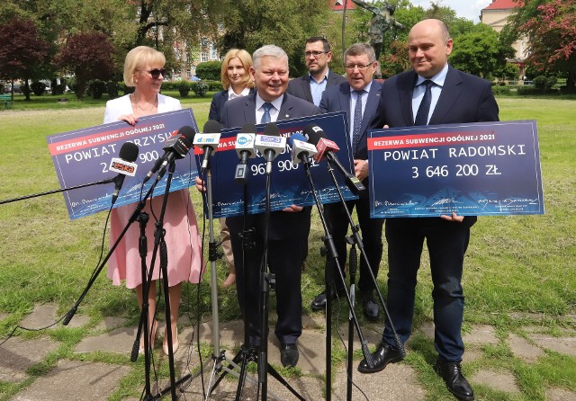 Poseł Marek Suski (w środku) wraz z parlamentarzystami PiS i radnymi, prezentują symboliczne czeki z kwotami dotacji.