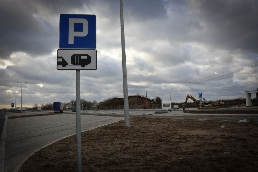 Stróż w zdezelowanej przyczepie pilnuje nowoczesnej drogi i parkingu