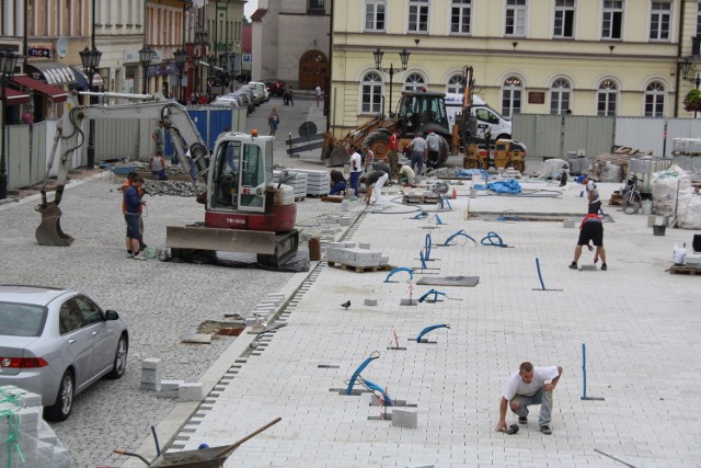 Ekipy budowlane układają kostkę na płycie głównej