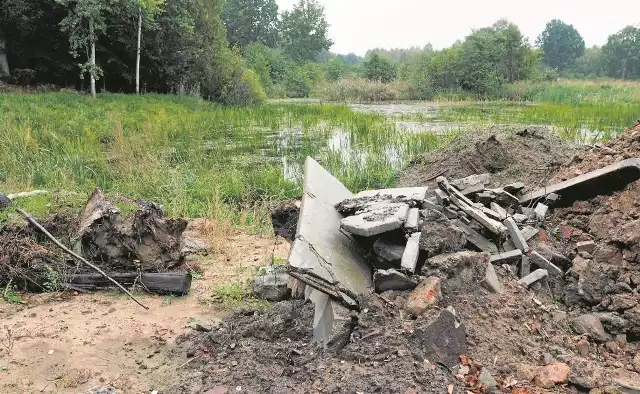 Na brzegu naturalnego zbiornika leżą hałdy ziemi i gruzu. Właściciel terenu wskazuje, że zostały tu przywiezione nielegalnie przez obce osoby, a on sam niecki opadowej zasypywać nie zamierza.