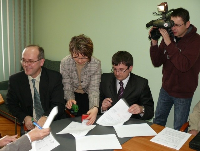 Uśmiechnięty starosta Władysław Pracoń i jego zastępca Krzysztof Krawiec podpisują umowy z wykonawcami.