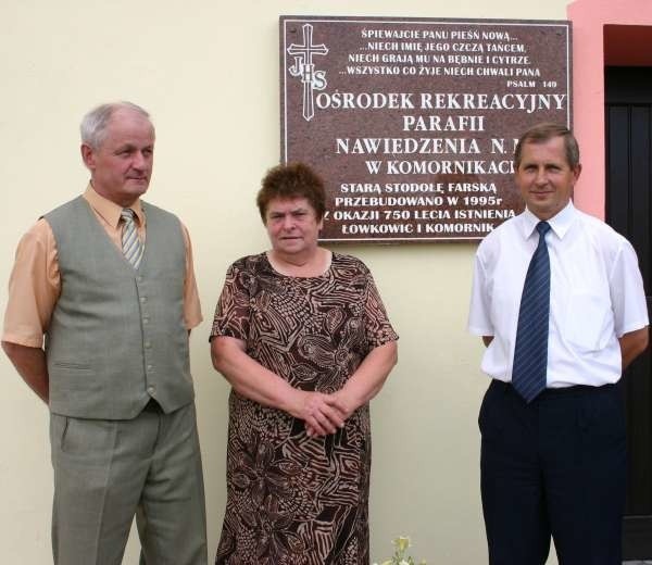 Jan Galer, Anna Ridel i Hubert Jaskółka na tle tablicy upamiętniającej niezwykły czyn społeczny parafian.