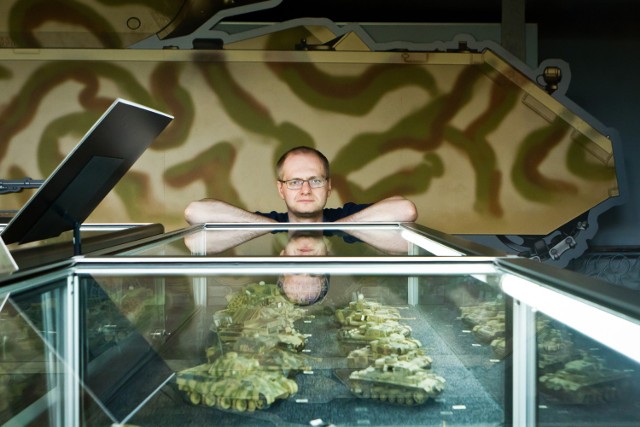 Łukasz Nadolski z Muzeum Wojsk Lądowych prezentuje część modeli czołgów. W tle makieta 1:1 superciężkiego czołgu Maus