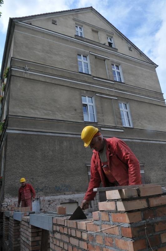 Murarz Czesław Herkt z zakładu usługowo-remontowego z Nowego Miasta nad Wartą stawia ścianę nowego skrzydła ratusza