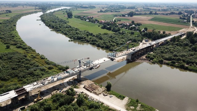 Z prędkością pięć metrów na tydzień postępują prace związane z budową mostu na Wiśle w Nowym Korczynie. Drogowcy realizują obecnie ostatnie dwa segmenty ciągu głównego, który połączy województwa świętokrzyskie i małopolskie. Wiemy już kiedy most połączy oba brzegi. Zobaczcie niesamowite zdjęcia z drona jakie zrobił Dawid Łukasik z "Echa Dnia" w sobotę 25 lipca 