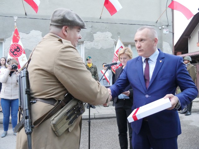 Przewodniczący Rady Miejskiej Stanisław Sobieraj wręcza flagę Dariuszowi Krasoniowi przed siedzibą Kedywu