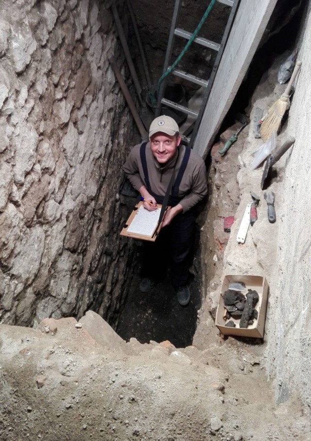 Archeolog wawelski Paweł Kajfasz przy odkrytym murze w wykopie, w kt&oacute;rym prowadził badania