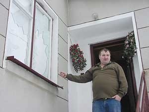 Jan Malon pokazuje wybite szyby w oknach