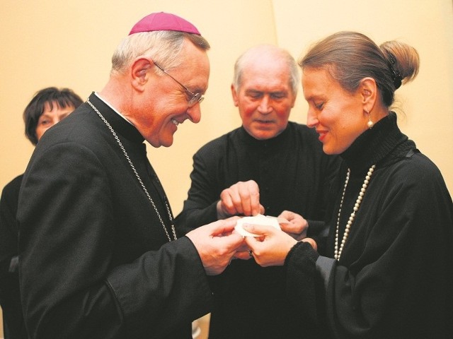 Biskup Edward Dajczak dzieli się opłatkiem z członkinią słupskiego chóru ZNP. W tle Anna Skotnicka z tego chóru i ksiądz Jan Giriatowicz, proboszcz parafii św. Jacka.