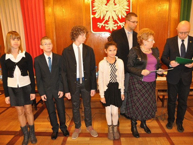 Od lewej najlepsi uczniowie podstawówek: Michalina Dybowska, Jakub Brusiło, Kasajan Cakoli odbierają stypendium z rąk burmistrza Jerzego Hardie-Douglasa (z prawej).