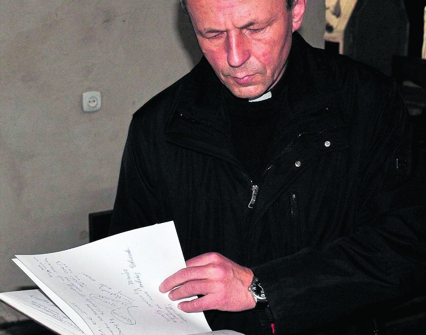 Ksiądz Jerzy Burek pokazuje księgę z prośbami  do św....