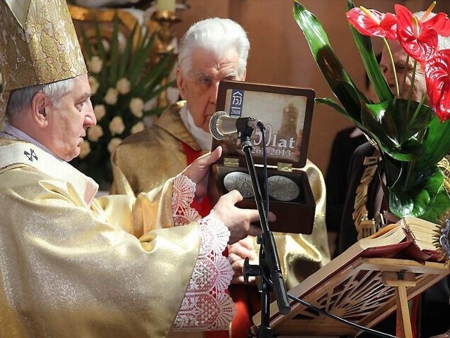 Prymas pokazuje medal zgromadzonym w kościele pw. św. Floriana