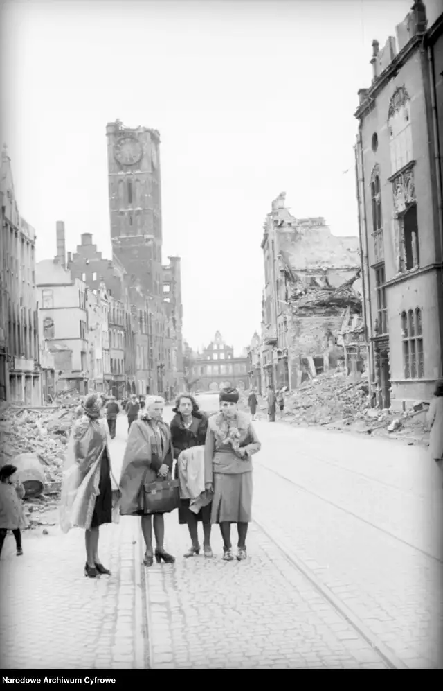 Grupa kobiet na ul. Długiej. W tle budynek ratusza Głównego Miasta z uszkodzoną wieżą oraz w tle ruiny Zielonej Bramy (czerwiec 1945) 