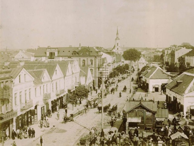 Jedno ze zdjęć Aleksandra Sołowiejczyka, wykonane w 1898 roku. Na pierwszym planie plac targowy wokół Ratusza. W głębi widać wieżę białego kościółka &#8211; dzisiaj zdominowaną przez bryłę bazyliki.