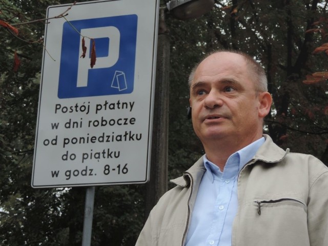 Marek Browiński, a obok niego prawidłowa tablica oznaczająca strefę płatnego parkowania