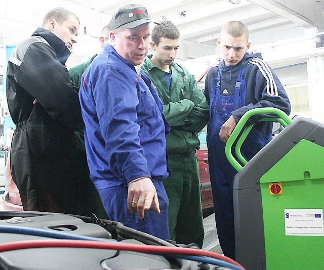 Nauczyciel Mirosław Jasieniecki pokazuje uczniom jak obsługiwać urządzenie do obsługi i konserwacji klimatyzacji
