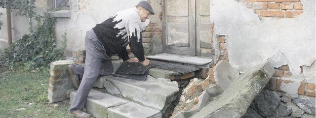Franciszek Zadorewski na rozpadających się schodach domu swego sąsiada. Pokazuje miejsce, którym wychodzą szczury.