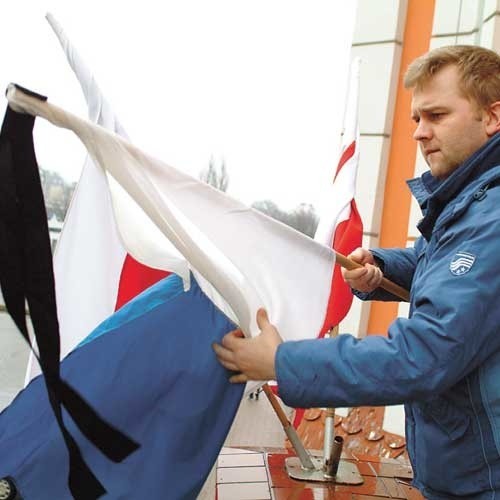 Andrzej Sokołowski zawiązuje kir przy fladze narodowej wiszącej przy budynku świdwińskiego starostwa.
