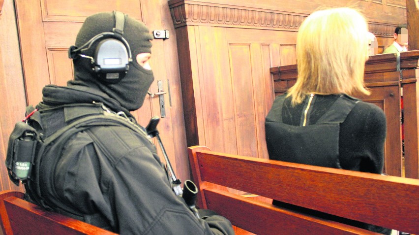 Oskarżona Magda G. w kamizelce kuloodpornej, pilnowana przez...