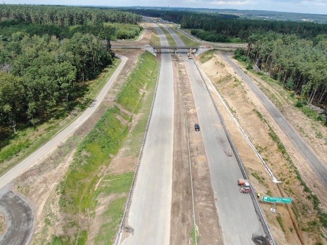 Letnia pogoda sprzyja prowadzeniu prac przy budowie ponad 14-kilometrowego odcinka drogi ekspresowej S3 pomiędzy Kaźmierzowem a Lubinem. - Zaawansowanie robót na tym odcinku wynosi prawie 84 proc. Wykonawca kontynuuje prace związane z realizacją robót bitumicznych na drogach technologicznych i niektórych odcinkach trasy głównej.  Wykonywane są dowiązania do obiektów mostowych, gdzie wymieniane były dylatacje i ich naprawy zostały zakończone – informuje dolnośląski oddział Generalnej Dyrekcji Dróg Krajowych i Autostrad.  Przypomnijmy, że na placu budowy działa obecnie nowy wykonawca, który przejął niedokończoną inwestycję po włoskim konsorcjum, z którym została zerwana umowa. Okazało się, że sporo elementów było wykonanych wadliwie i konieczne były naprawy. Wszystko jednak wskazuje, że w listopadzie ten odcinek trasy S3 zostanie udostępniony kierowcom. W najbliższych dniach planowane jest betonowanie naprawionych już dylatacji oraz wykonywanie nawierzchni z asfaltu lanego na niektórych obiektach. Trwają prace wykończeniowe, m.in. montaż słupów i wypełnień ekranów akustycznych oraz barier. Na węzłach i MOP-ach montowane są oprawy oświetleniowe. Trwają prace związane z wykańczaniem zespołów oczyszczających na kanalizacji deszczowej. Zakończono budowę zbiorników retencyjnych i przebudowę rowów melioracyjnych, w tym cieku Moskorzynka. Pod koniec sierpnia wykonawca rozpocznie układanie nawierzchni na trasie głównej. Wideo: Droga S3 w Lubuskiem