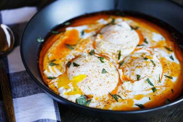 Jajka po turecku to danie składające się z jajek w koszulce, podgrzanego gęstego jogurtu z czosnkiem i polane brązowym masłem. Świetna propozycja na weekendowe śniadanie.