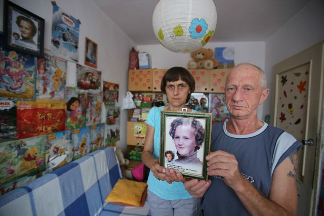 Rodzice Basi z jej portretem (progresja) w pokoju dziewczynki i rodzinne fotografie
