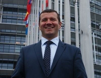 Łukasz Kulik przed siedzibą Parlamentu Europejskiego