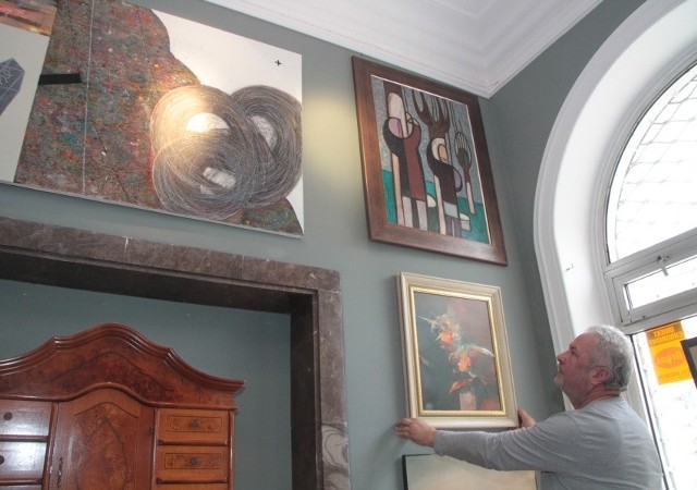 Bogusław Gradka zawiesza obrazy na ścianach nowej galerii.