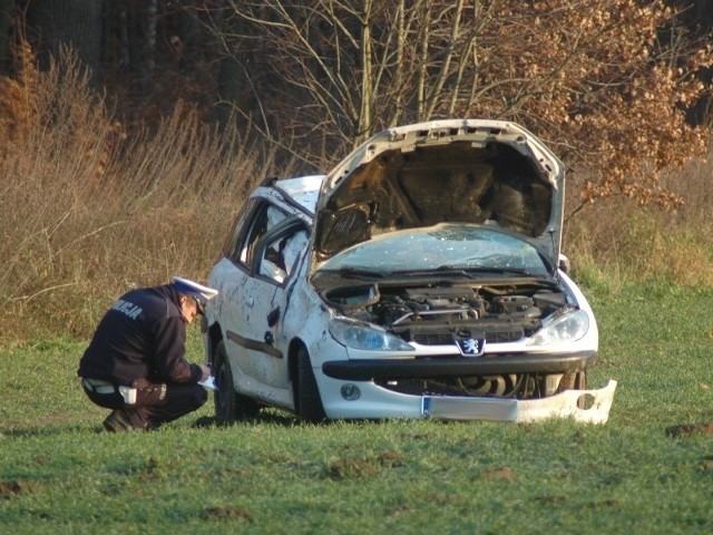 Policjant prowadzi oględziny rozbitego samochodu