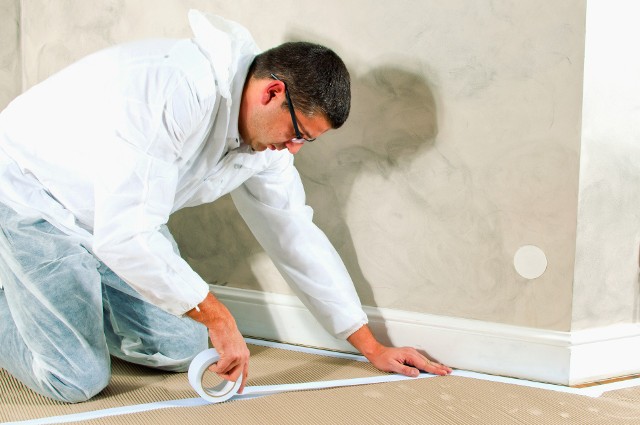 Przygotowanie pomieszczenia do malowaniaMocowanie tektury falistej w celu zabezpieczenia podłogi przed malowaniem mieszkania.
