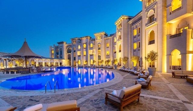 To właśnie w tym miejscu reprezentacja Polski zatrzyma się w Katarze na mistrzostwa świata 2022. Ezdan Palace Hotel to wyjątkowy obiekt w Doha, oferujący najwyższy poziom luksusu.Położony pomiędzy starą i nową Dohą, w pobliżu największych centrów handlowych w Katarze, pięciogwiazdkowy Ezdan Palace Hotel podnosi poprzeczkę w zakresie obsługi, stylu i czystego luksusu. Otwarty w maju 2018 roku hotel wyróżnia się wyrafinowaną andaluzyjską architekturą i wyjątkową obsługą, która łączy prawdziwą bliskowschodnią gościnność z międzynarodowymi standardami.195 bogato wyposażonych pokoi i apartamentów zostało starannie zaprojektowanych przez znanego architekta, aby zapewnić komfort wszystkim gościom. Trzy znakomite restauracje oferują wykwintne doznania kulinarne, serwując dania kuchni międzynarodowej, włoskiej i tajskiej.Hotel położony jest przy Al Shamal Road, zaledwie 30 minut od międzynarodowego lotniska Hamad, w pobliżu głównych dzielnic biznesowych i rozrywkowych Doha.