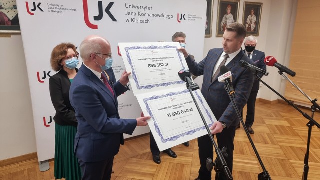 Minister Przemysław Czarnek przekazuje czeki na około 12 milionów na ręce profesora Stanisław Głuszka, rektora Uniwersytetu Jana Kochanowskiego w Kielcach.