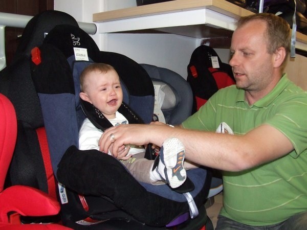 Andrzej Zieliński, tata ośmiomiesięcznego Błażejka, sprawdza, czy maluchowi będzie wygodnie w foteliku.  