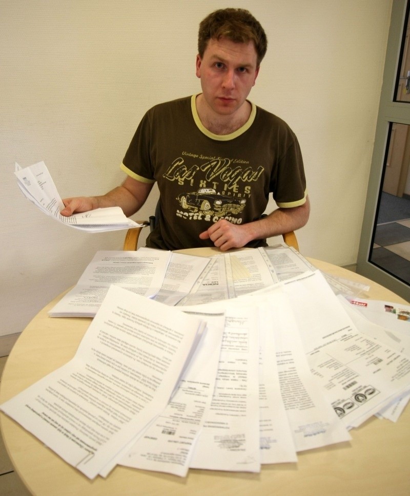 Mateusz Pielas pokazuje stos dokumentów, jakie powstały w...