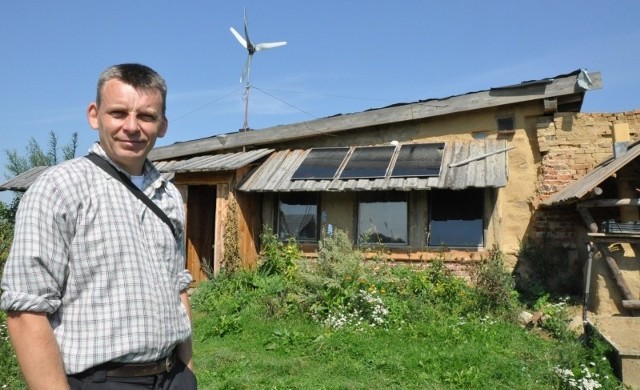Adam Ulbrych, ekolog z Komorzna, przed swoim prowizorycznym domem zbudowanym po pożarze.