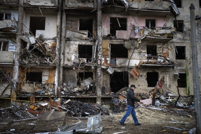 Mężczyzna na tle zbombardowanych przez rosyjską armię mieszkań, 25.02.2022. (AP Photo/Emilio Morenatti)