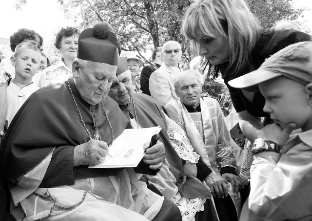 Biskup senior Ignacy Jeż podpisuje książkę o Ojcu Pio, którą za chwilę wręczy Tymoteuszowi Kurtiakowi.