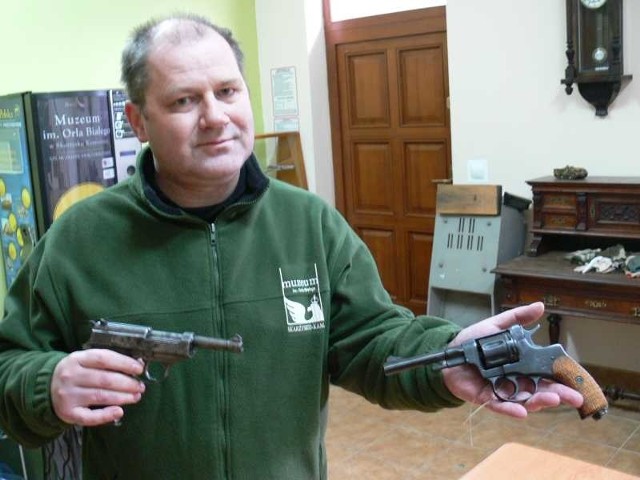 Tadeusz Sikora z Muzeum Orła Białego prezentuje dwa z otrzymanych od policji eksponatów. W lewej ręce trzyma radziecki rewolwer nagant, w prawej pistolet P 08 parabellum - takim posługiwał się filmowy kapitan Kloss.