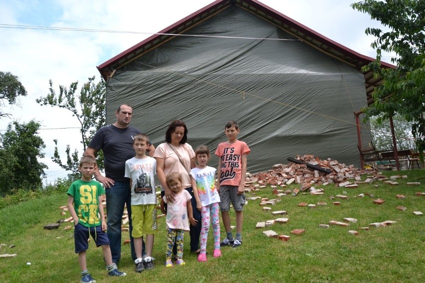 Rodzina państwa Maczugów z dziećmi przed zniszczonym domem.