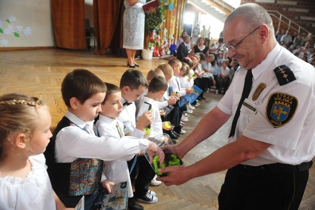 St. insp. Marek Boczkowski rozdaje odblaski uczniom pierwszych klas szkoły podstawowej nr 29.