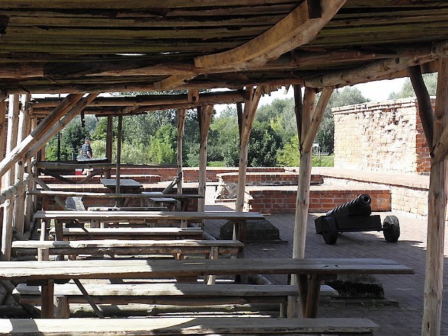 Na terenie ruin brodnickiego zamku pod zadaszeniem są ustawione drewniane stoły i ławy